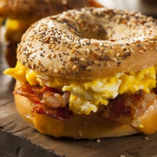 Close-up of a Fresco Foodworks breakfast bagel with scrambled eggs, bacon, and cheese.
